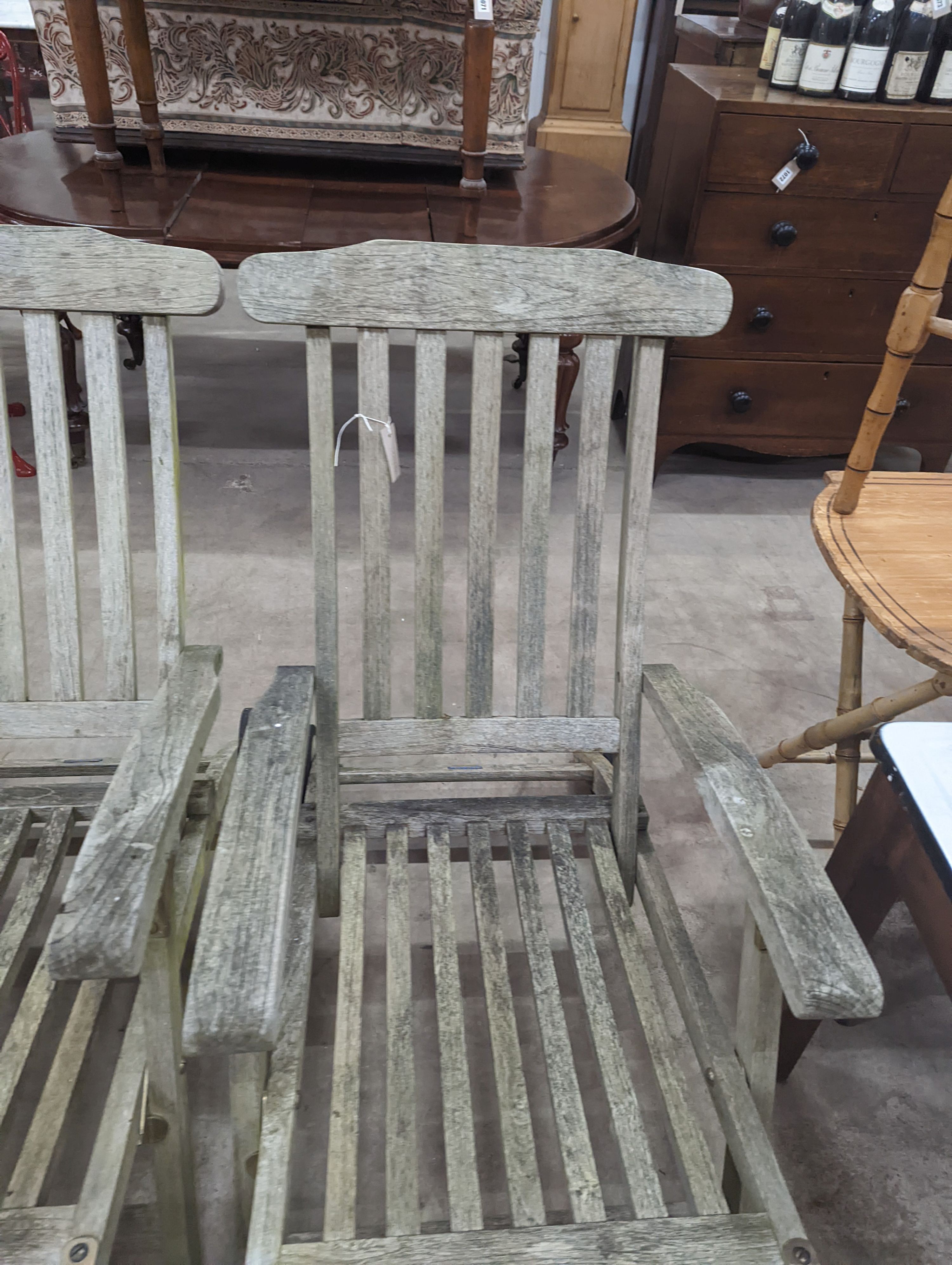 A pair of slatted weathered teak garden steamer chairs, width 59cm, height 97cm
